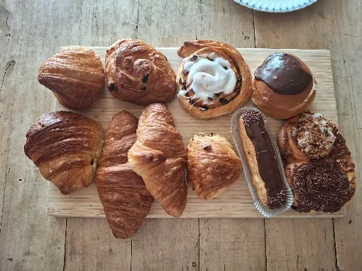 Koffiekoeken, gebak en patisserie op een houten plank: croissants, een eclair en andere lekkernijen